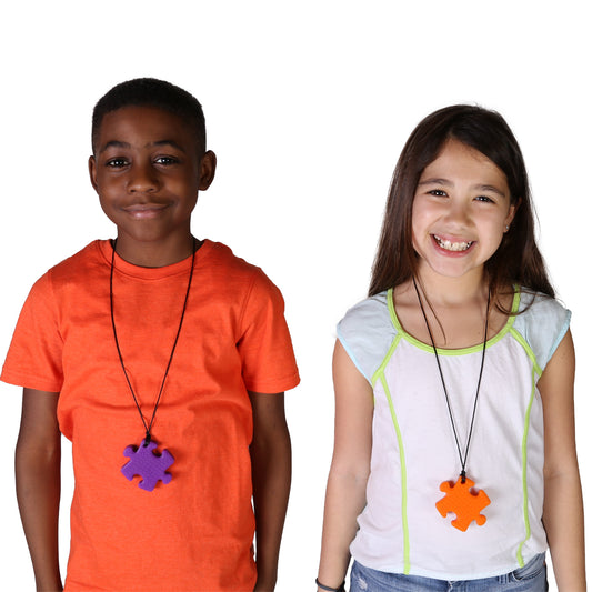 boy and girl smiling while wearing the Puzzle Piece Chewy necklaces