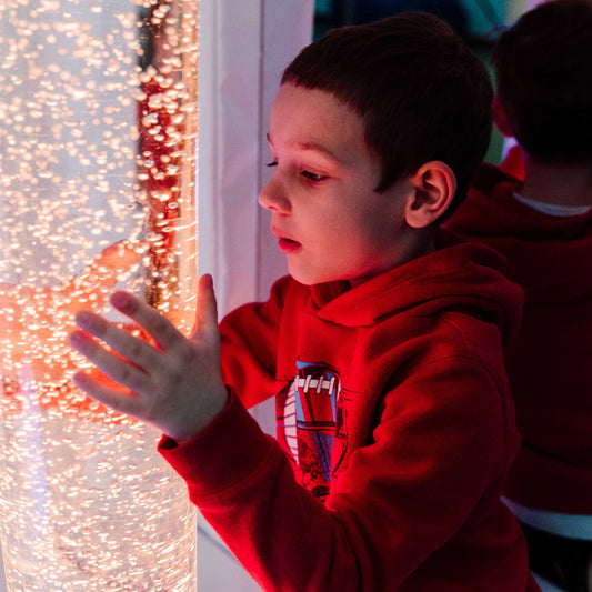 boy holding the brightly-colored Calming LED Bubble Tube
