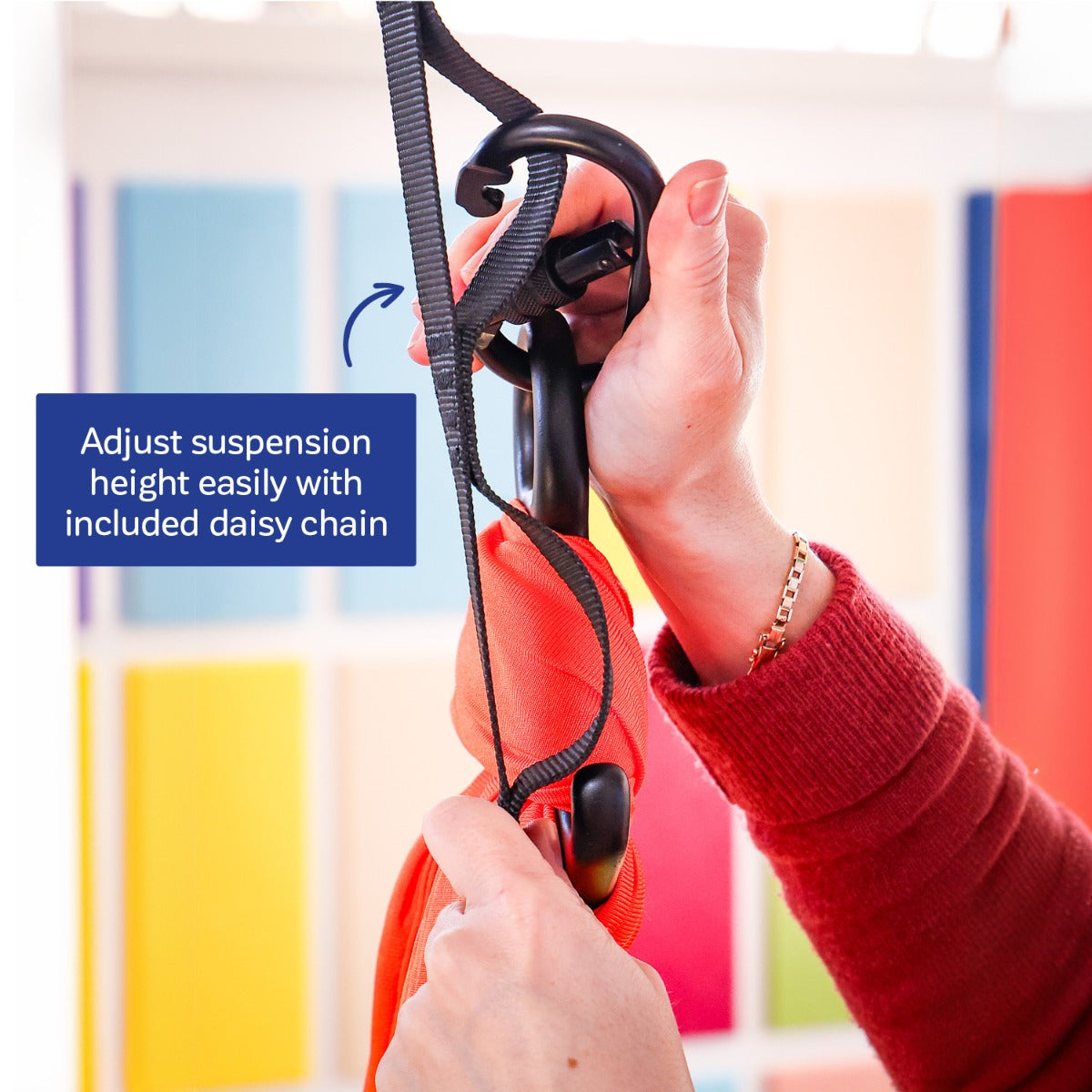 person adjusting the height of the orange Cozy Compression Swing