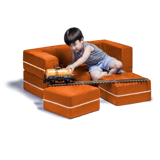 Child sitting on the orange Zipline Convertible Loveseat while playing with a train toy