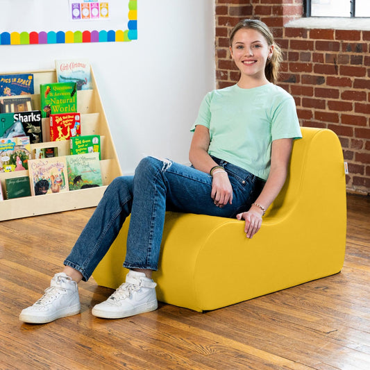 Girl smiling while sitting on the Sensory Wave Chair in the color yellow