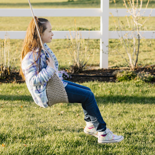 side view of girl swinging outdoors on the Macrame Doorway Swing