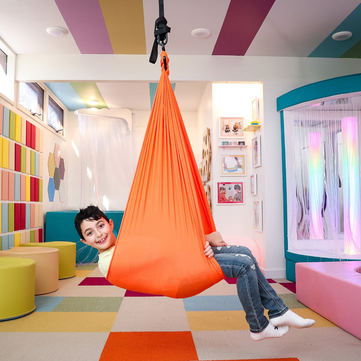 boy swinging indoors in orange Cozy Compression Swing