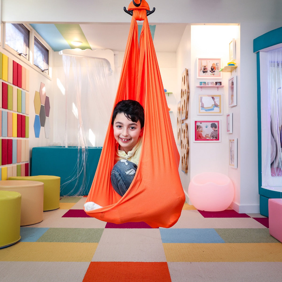 boy swinging indoors inside the orange Cozy Compression Swing