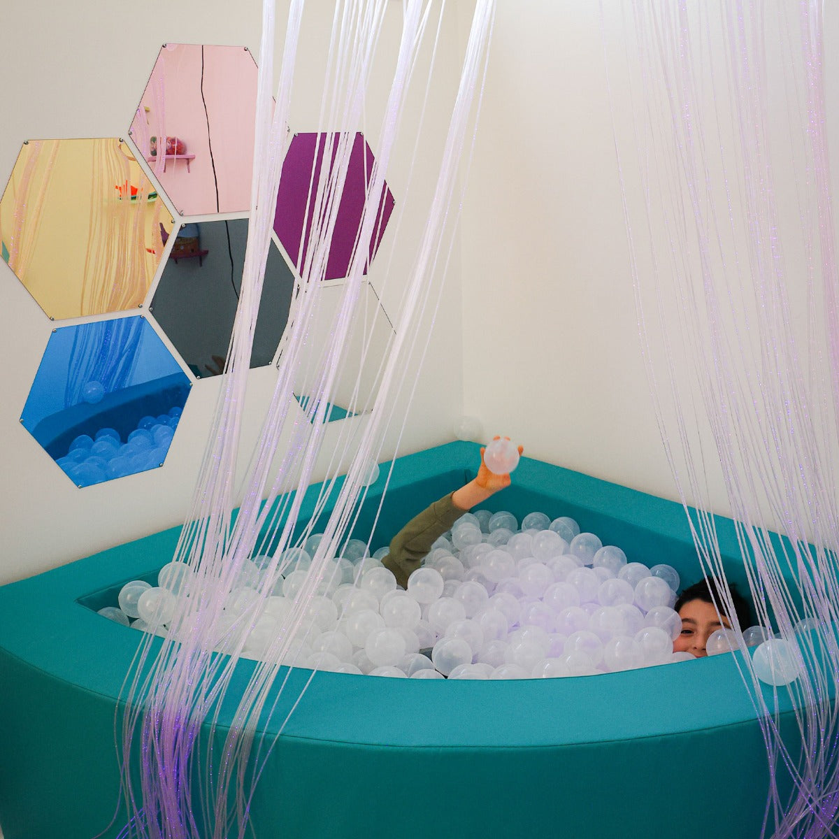 boy playing in a ball pit with Honeycomb Mirrors on the wall