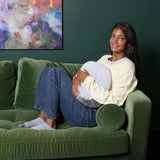 Girl on a sofa using the Hand-Hugger Weighted Pillow
 