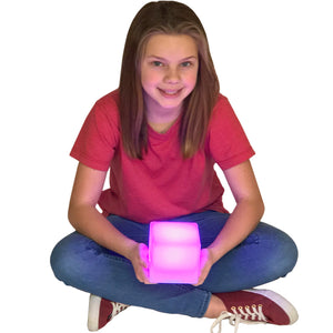 Girl smiling while sitting down and holding the LimeLite™ LED Cube