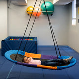 girl lying back on the Magic Carpet Swing indoors