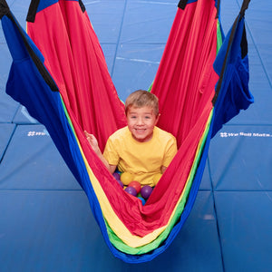 child sitting with balls in colorful acrobat hammock swing indoors