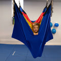 child in a colorful acrobat hammock swing hanging from the ceiling