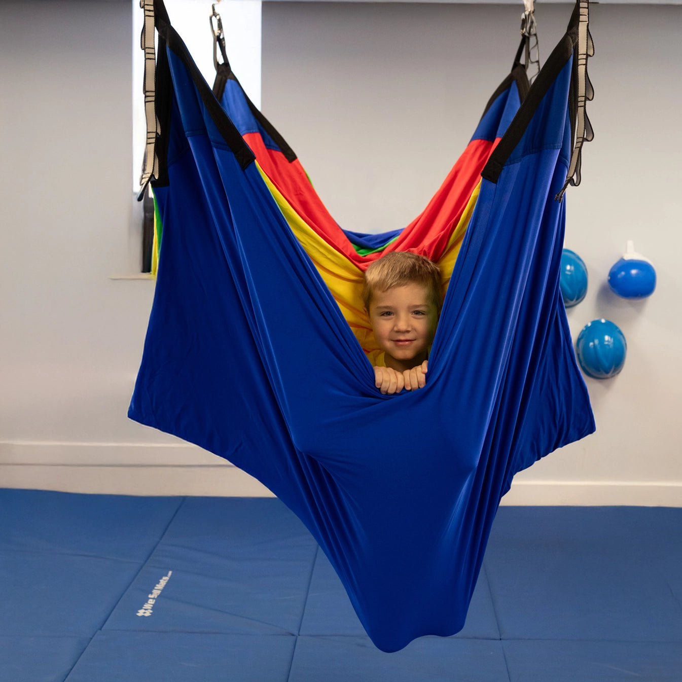 child in a colorful acrobat hammock swing hanging from the ceiling