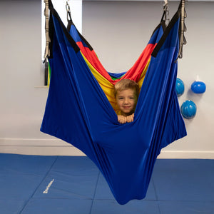 child in a colorful acrobat hammock swing hanging from the ceiling