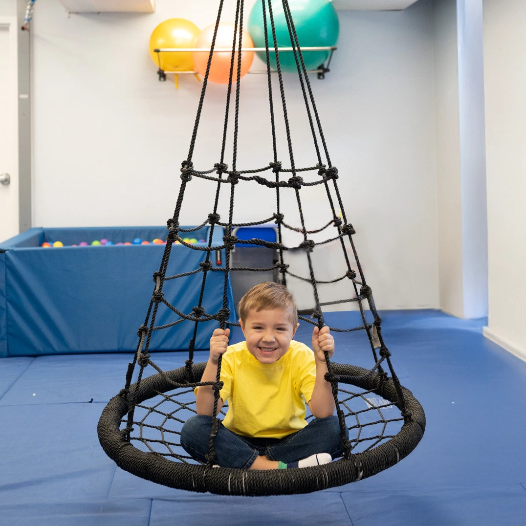 boy smiling while sitting on the black Web Tower Swing