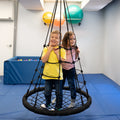 girl and boy smiling while standing on the black Web Tower Swing