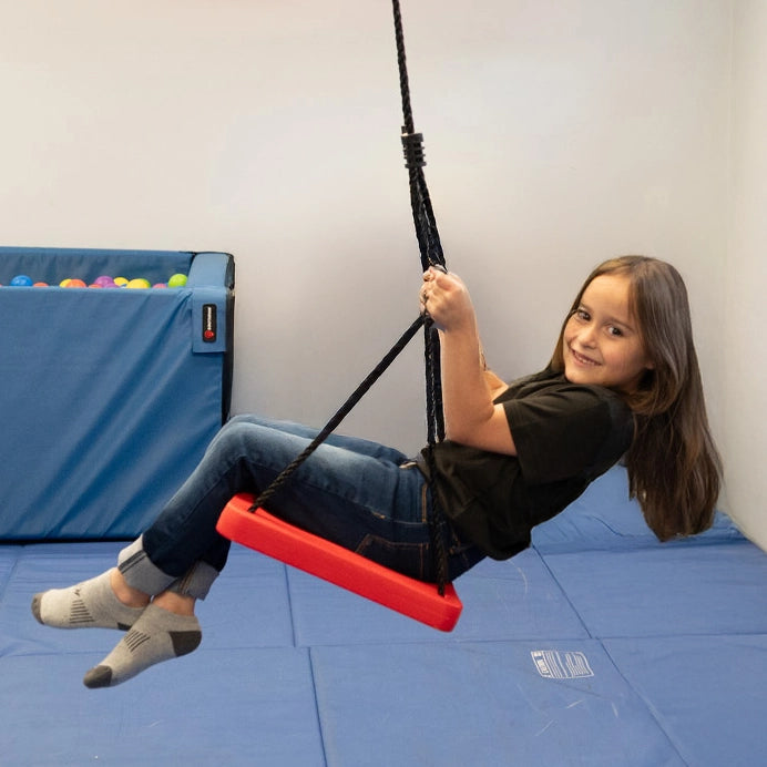 side view of girl sitting on the red Standing Swing indoors