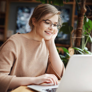 Girl sitting at a desk while smiling at her a laptop