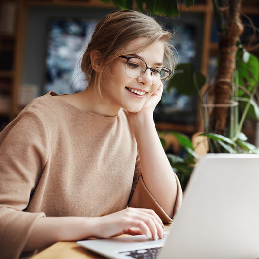 Girl sitting at a desk while smiling at her a laptop