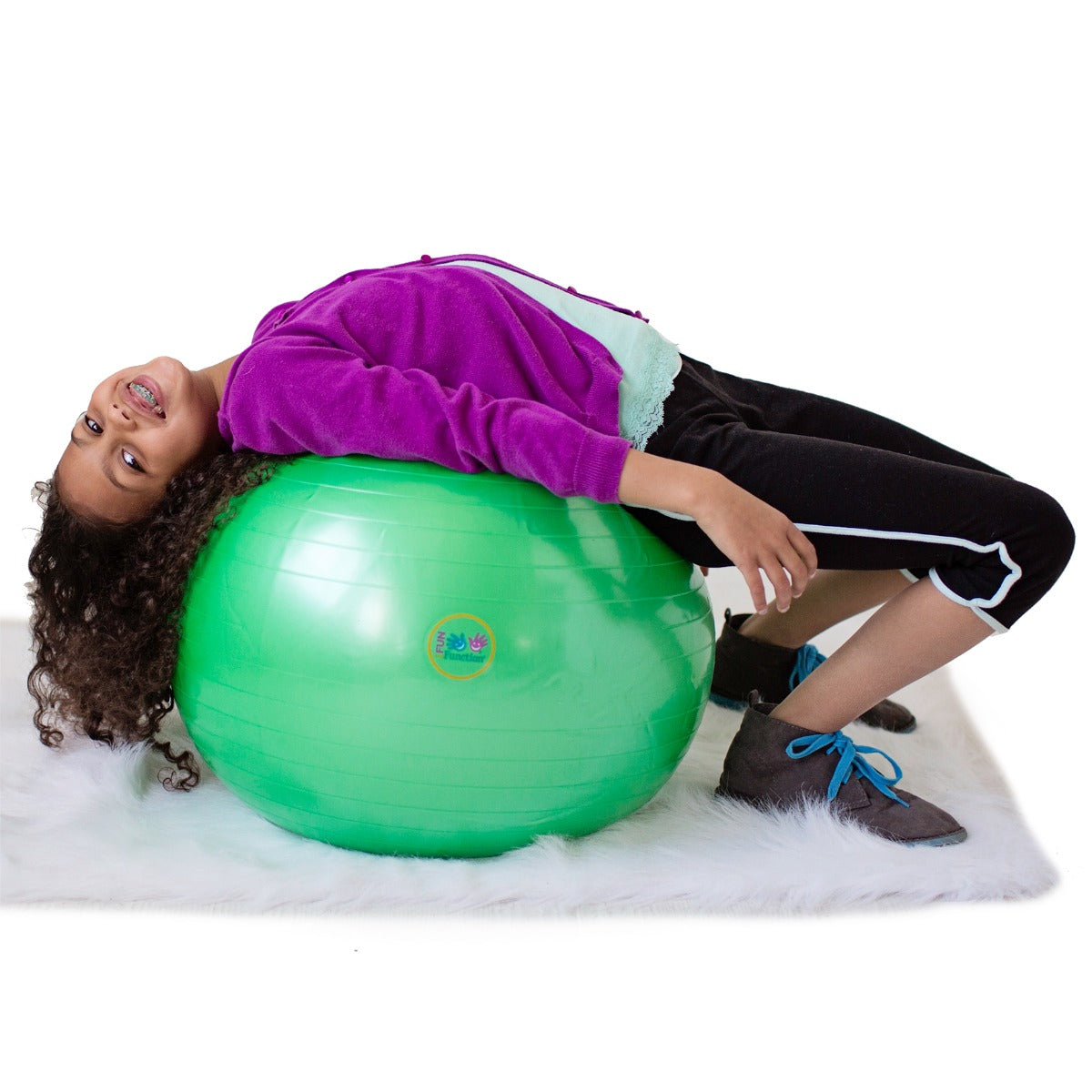 Girl smiling while laying on the green therapy ball