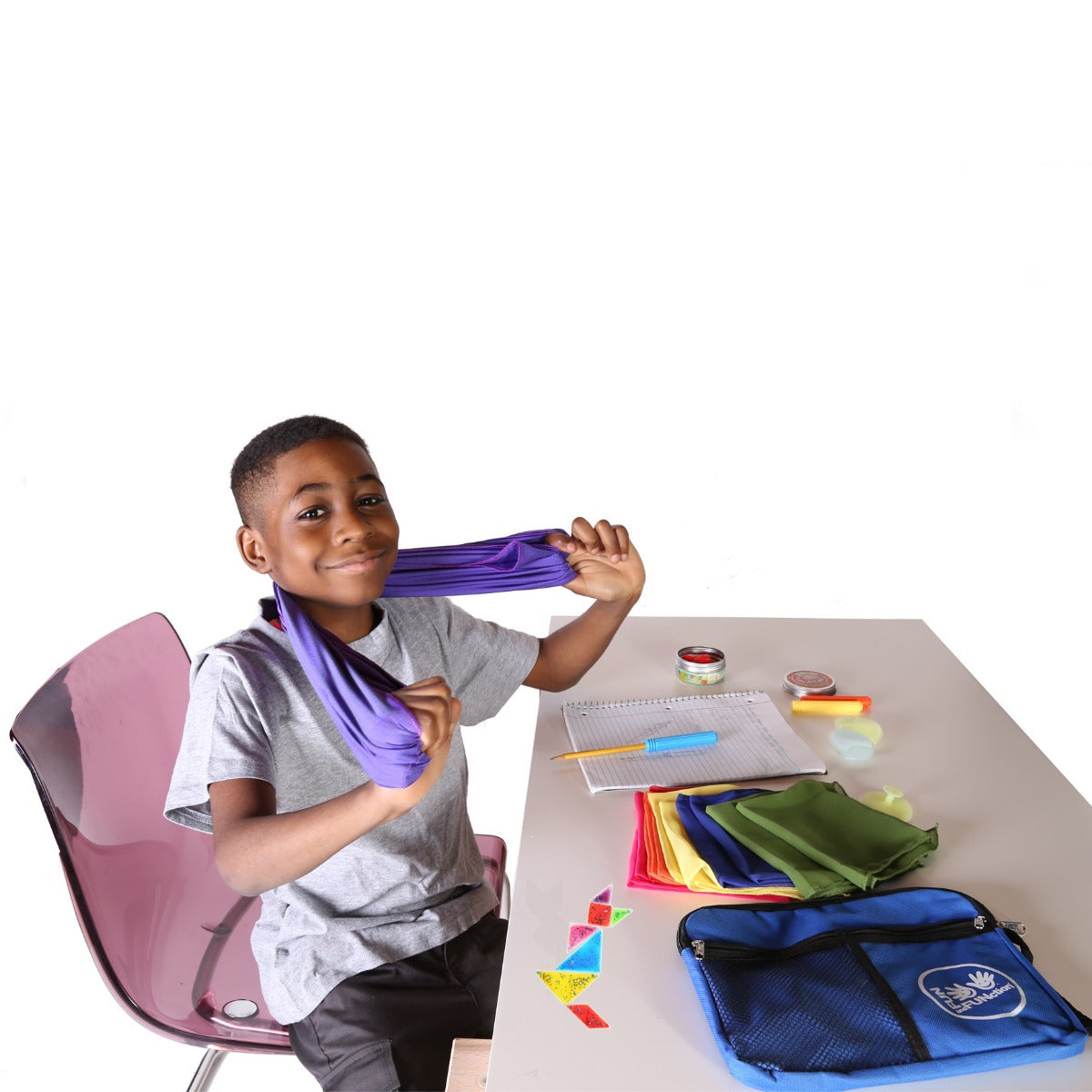 Boy smiling while sitting at a desk using the Sensory Survival Kit