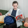 Girl reading while holding the Weighted Sensory Knot Ball