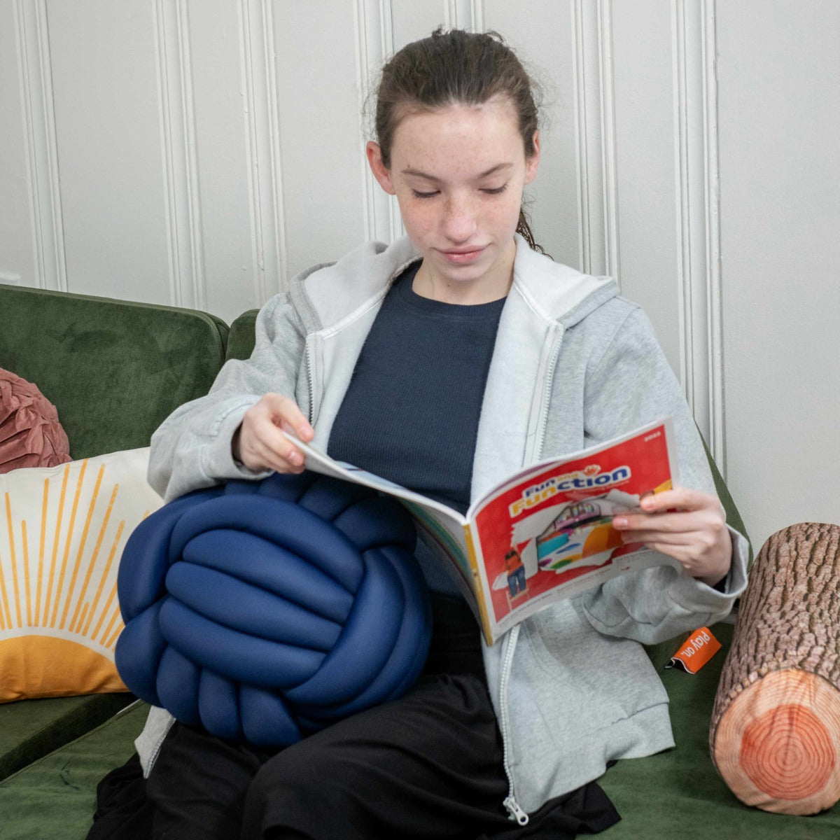 Girl reading while holding the Weighted Sensory Knot Ball
