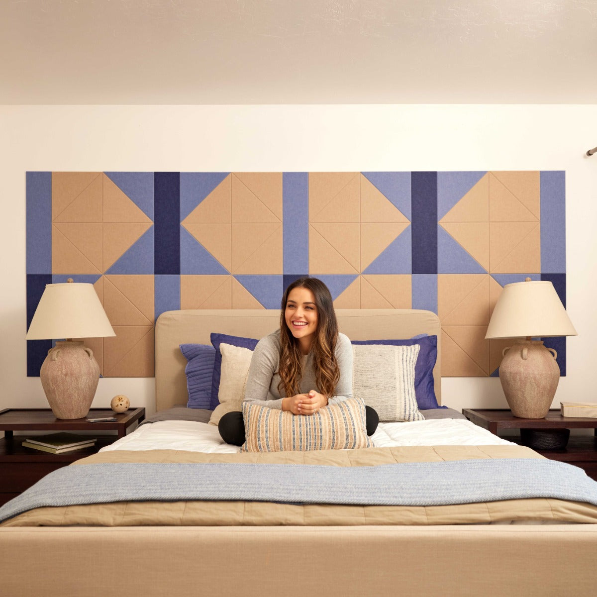 Woman smiling on a bed in a room with Felt Right Tiles Hourglass design