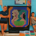 Two girls smiling and standing beside the LiteZilla Light Wall
