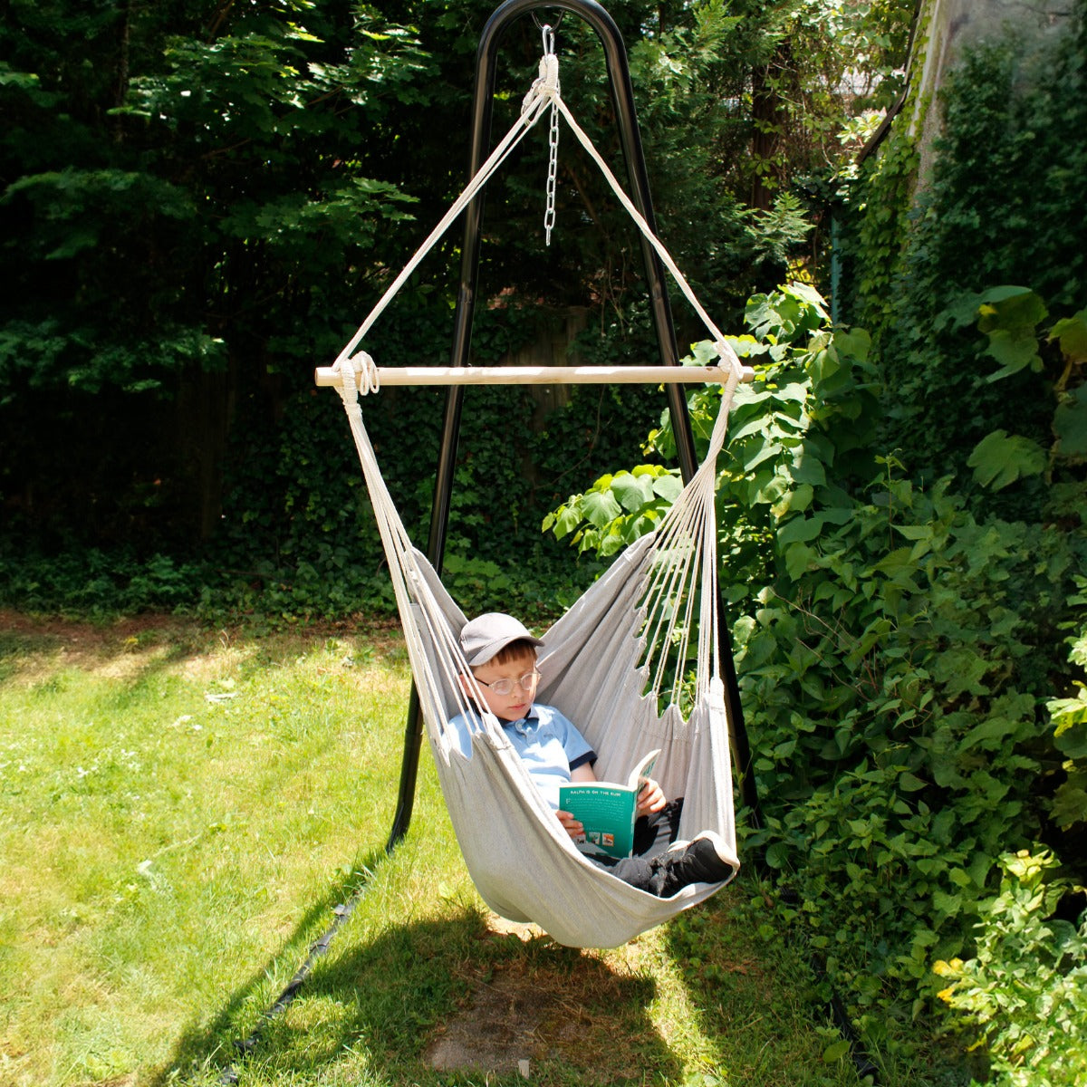 Boy reading while using the Hanging Hammock Chair in the garden