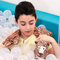 Boy in a ball pit using the Toby The Tiger Neck Pillow
