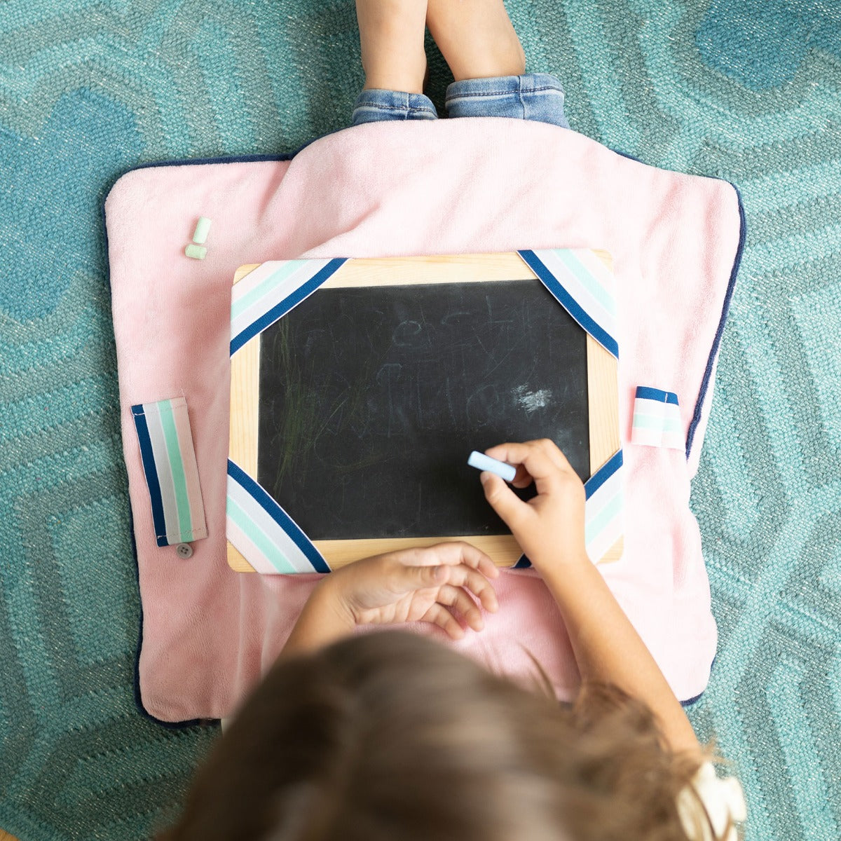 Child using the Sensory Basics Weighted Lap Pad with a chalk and board