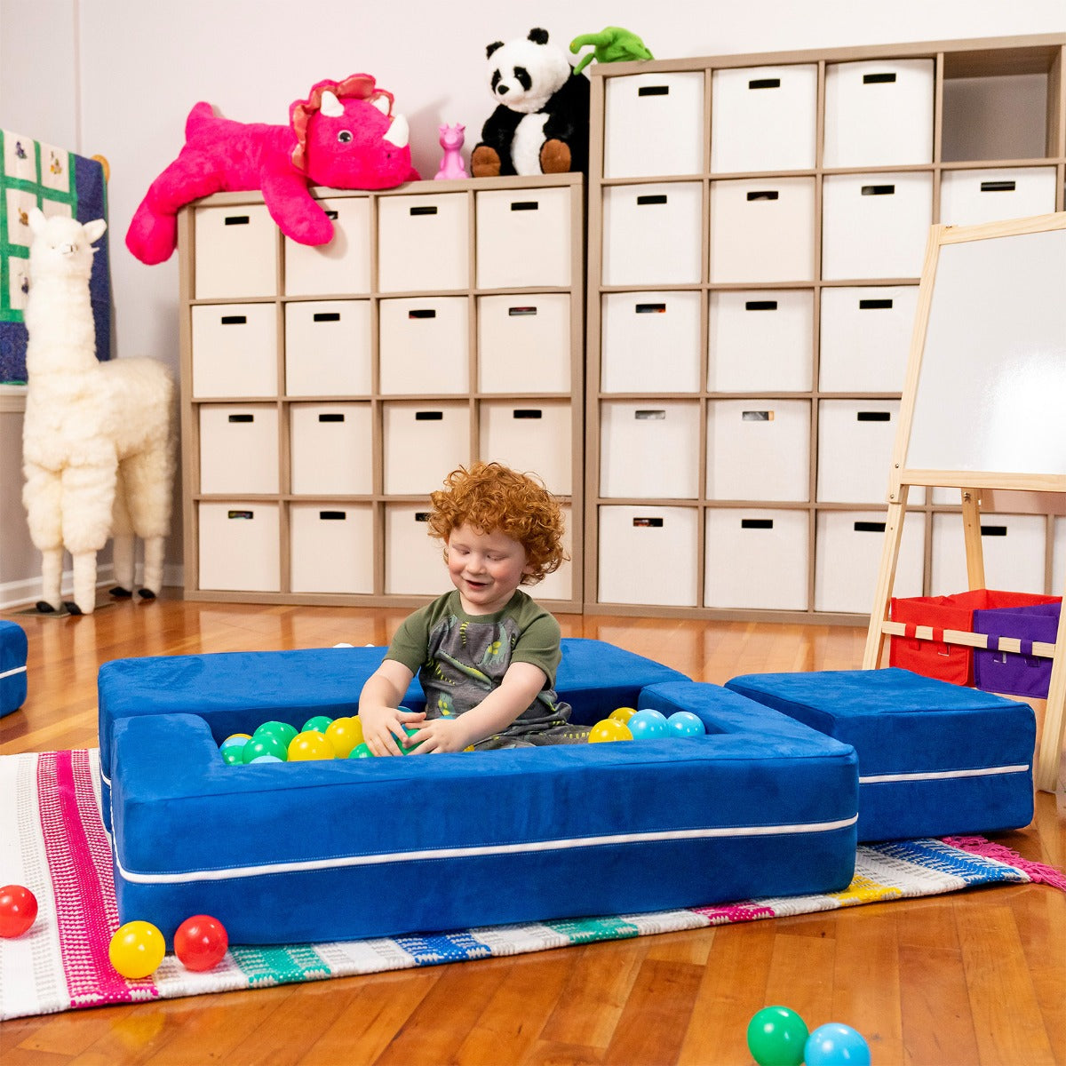 Child smiling while sitting and playing in the Zipline Convertible Loveseat