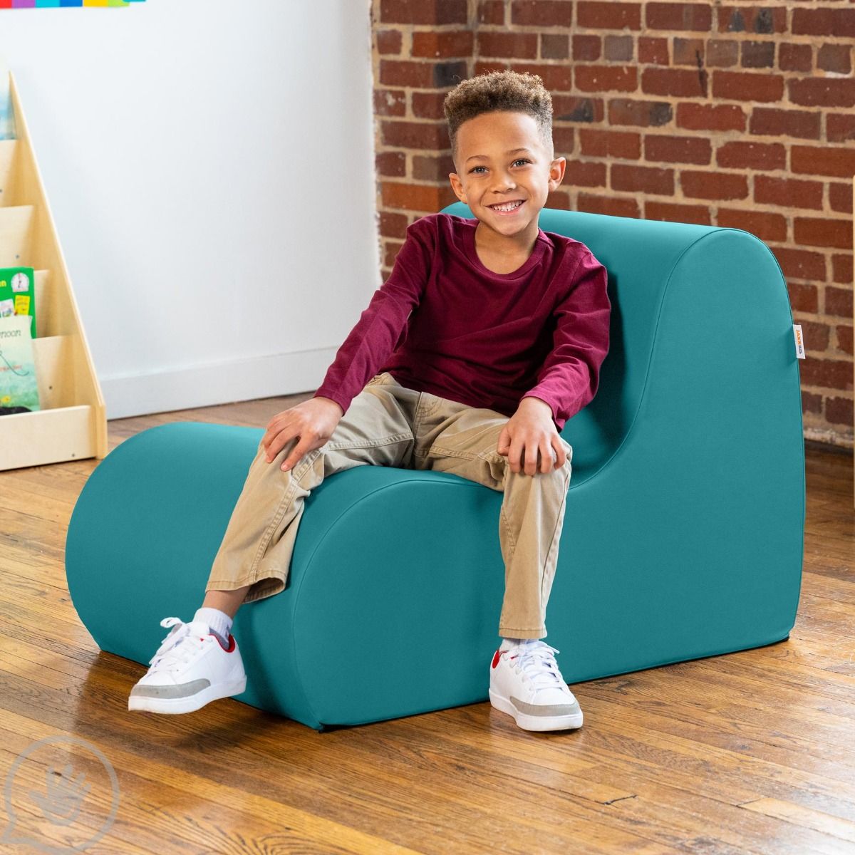 Boy smiling while sitting on a Sensory Wave Chair in the color turquoise