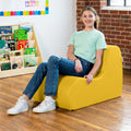Girl smiling while sitting on the Sensory Wave Chair in the color yellow