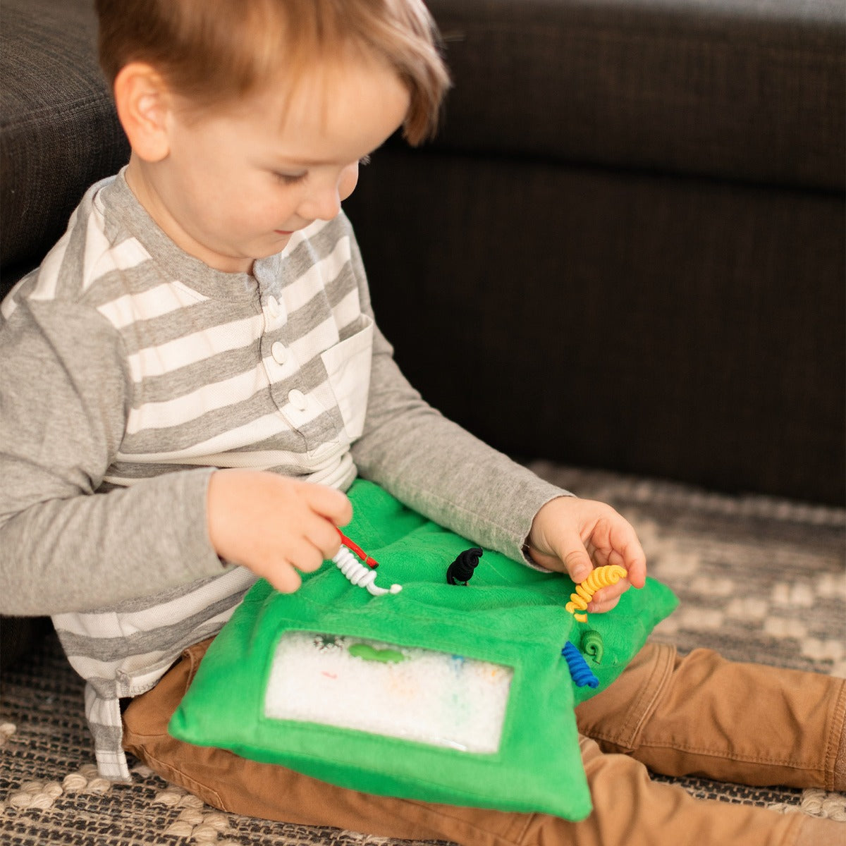Boy playing with the Busy Fingers™ Fidget Lap Pad