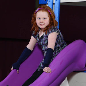 Girl smiling on the slide while wearing the Sensory Sleeves