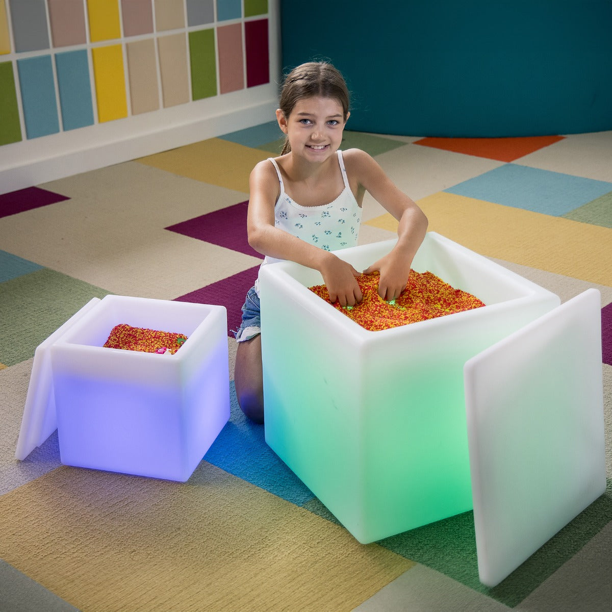 Girl playing with both size options of the LimeLite™ LED Sand Tables