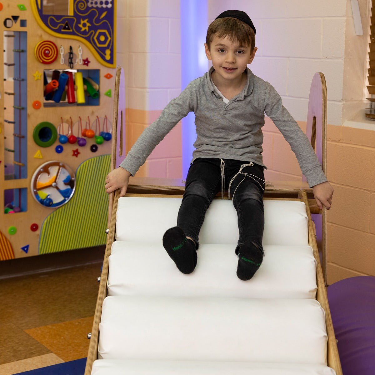Boy smiling at the top of the LED Sensory Roller Slide
