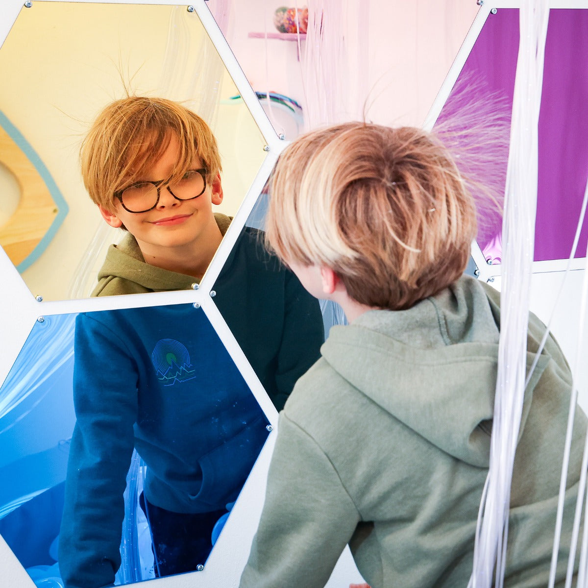 Boy smiling while looking at the Honeycomb Mirrors