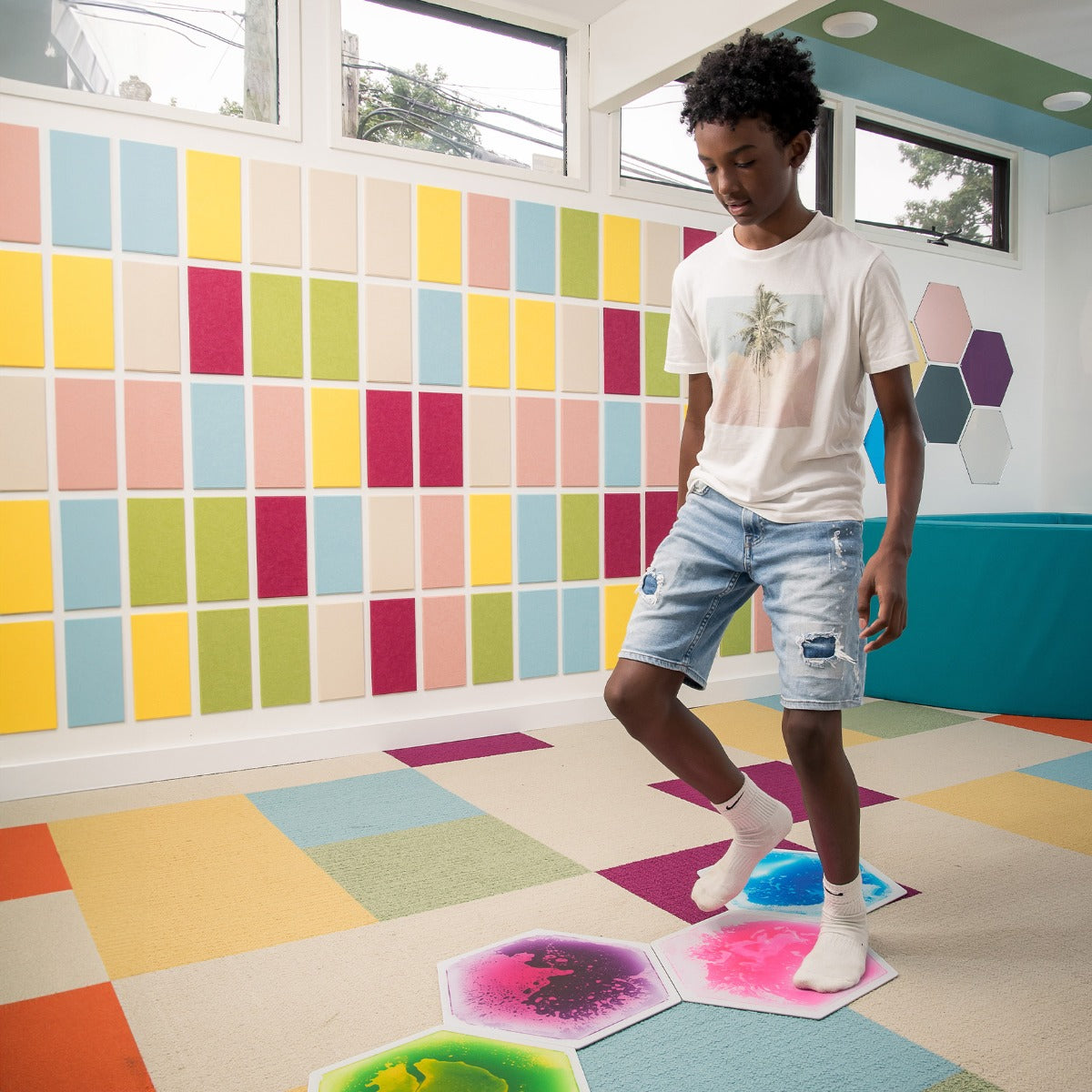 Child standing on a gel tile, watching colors swirl and shift