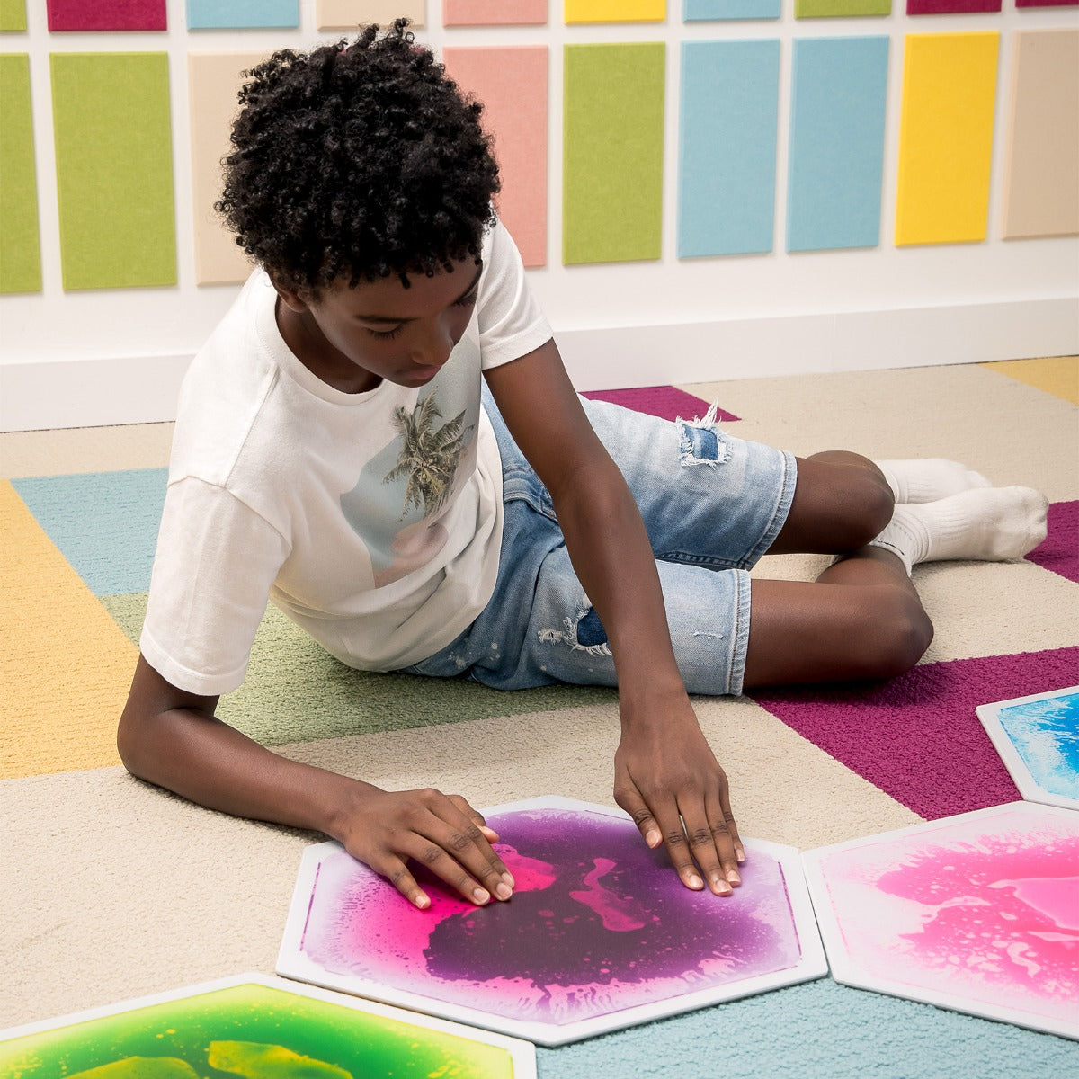 Child touching a gel tile, watching colors swirl and shift
