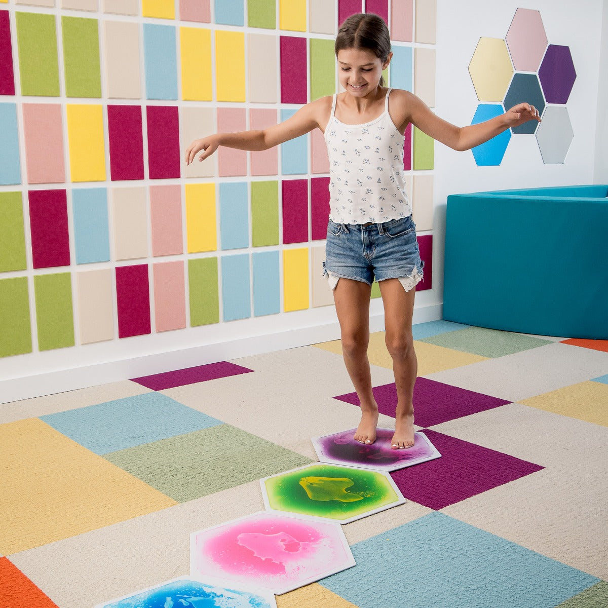 Child standing on a gel tile, watching colors swirl and shift