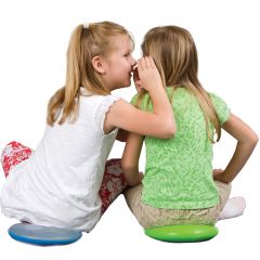 Child whispering to her friend while both sit on Squishy Gel Cushions in colors blue and green