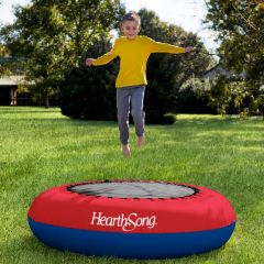 Boy smiling while jumping in the air on the Inflatable Trampoline in a garden 