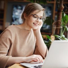 Girl sitting at a desk while smiling at her a laptop