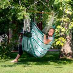 woman smiling while slaying in the comfy and colorful green and gray hammock-style chair