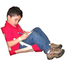 Young boy sitting comfortably in the red HowdaHug Seat while writing notes